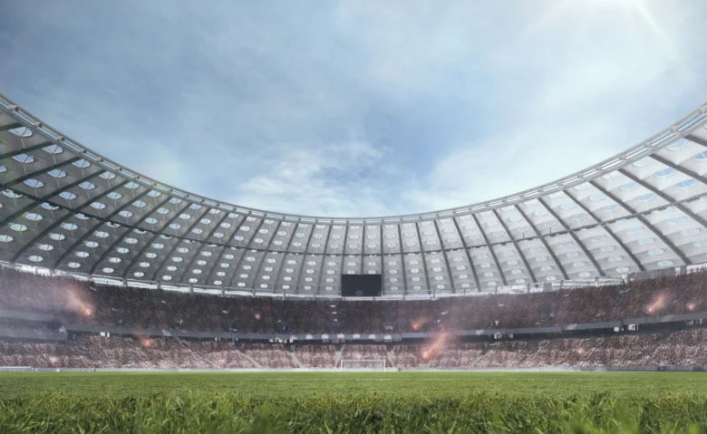 Vnitřní pohled na plně obsazené stadion s trávníkem.