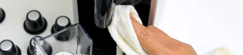 Ruka čistí páru kávovaru utěrkou po odvápnění.