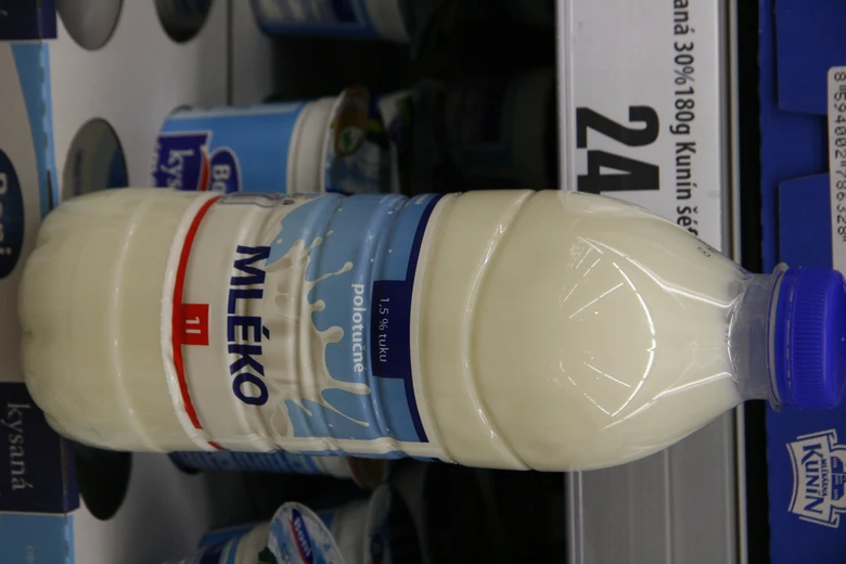 Plastová lahvička polotučného mléka na regálu v obchodě.