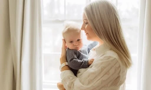 Mother holding baby near window