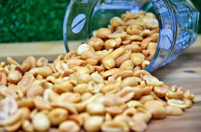 Ořechy arašídy vylije z sklenice na dřevěnou desku.