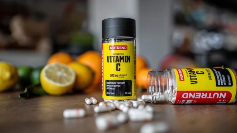 Fialka s vitamínem C a pilulky na dřevěné desce.