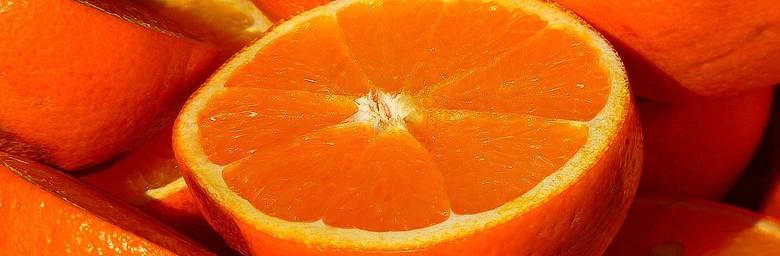 Čerstvý pomeranč rozkrojený na půlku s viditelnými segmenty.