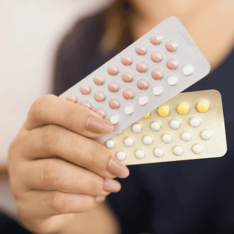 Ruce drží dvě balení hormonálních antikoncepčních pilulek.