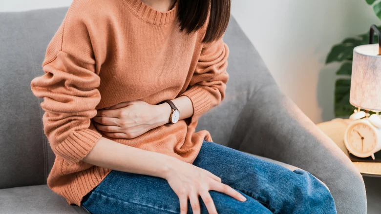 Žena drží břicho v bolesti při menstruačních křečích.