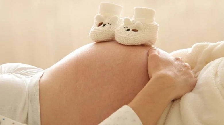 Těhotná břicho s rukou a dětskými botičkami