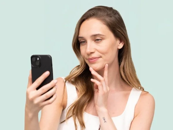 Žena se dívá na telefon s myšlenkou o péči o pleť.