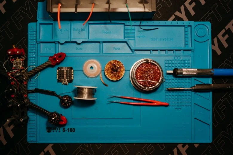 Modrá deska s pájecím materiálem a nástroji pro elektroniku.