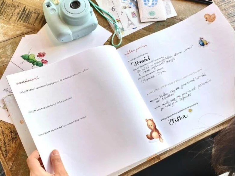 Otevřená knížka pro výběr jména dítěte s kamerou a dekoracemi.