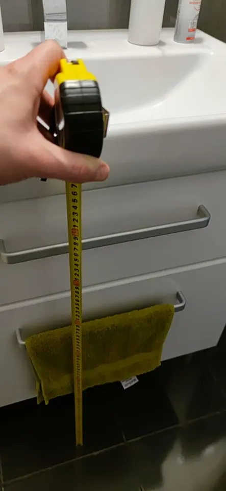 Měření výšky umyvadla páskou pro správný výběr koupelny.
