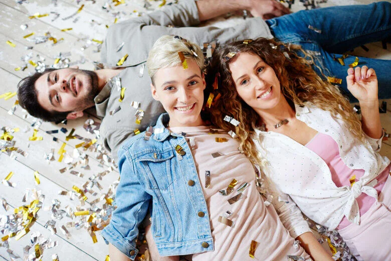 Three people lying on floor with confetti