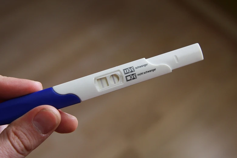 Rukou držená těhotenská zkouška s pozitivním výsledkem.