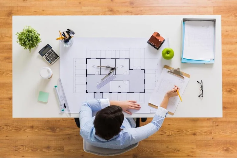 Architekt pracuje na plánech domu s nářadím a modely.