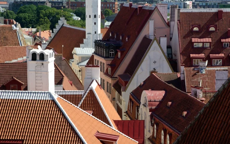 Červené taškové střechy historického města s komíny.