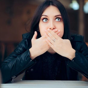 Žena překvapeně zakrývá ústa rukama a hledí nahoru.