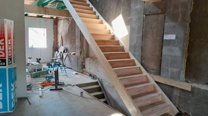 Dřevěné schodiště v stavbě s nástroji na podlaze.