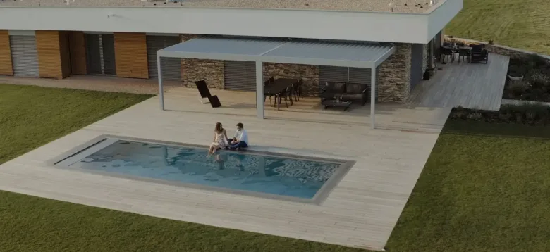 Moderní kovová pergola nad bazénem s osazenými sedacími místy.