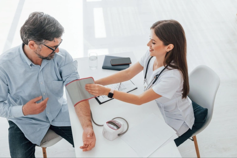 Lékařka měří krevní tlak u staršího muže v ordinaci.