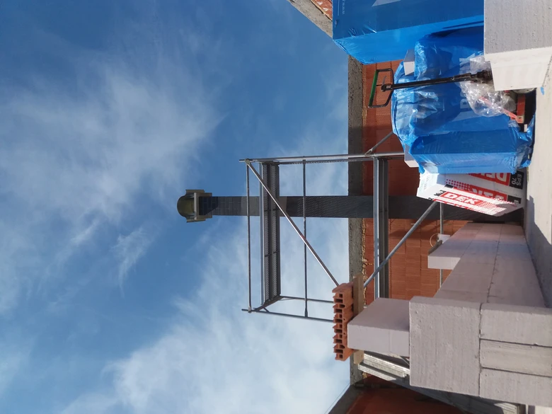 Nově instalovaný komín na střeše s lešení a materiály.