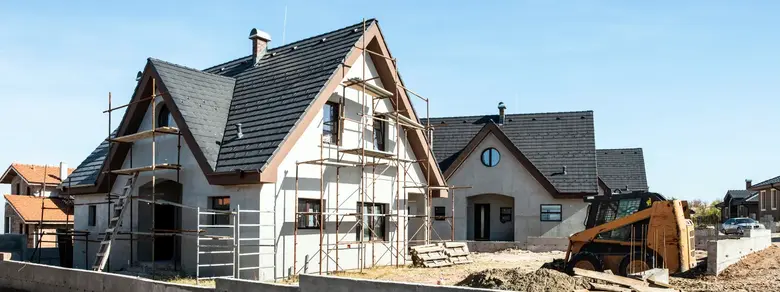 Dům v budování s lešeními na pozadí modrého nebe.
