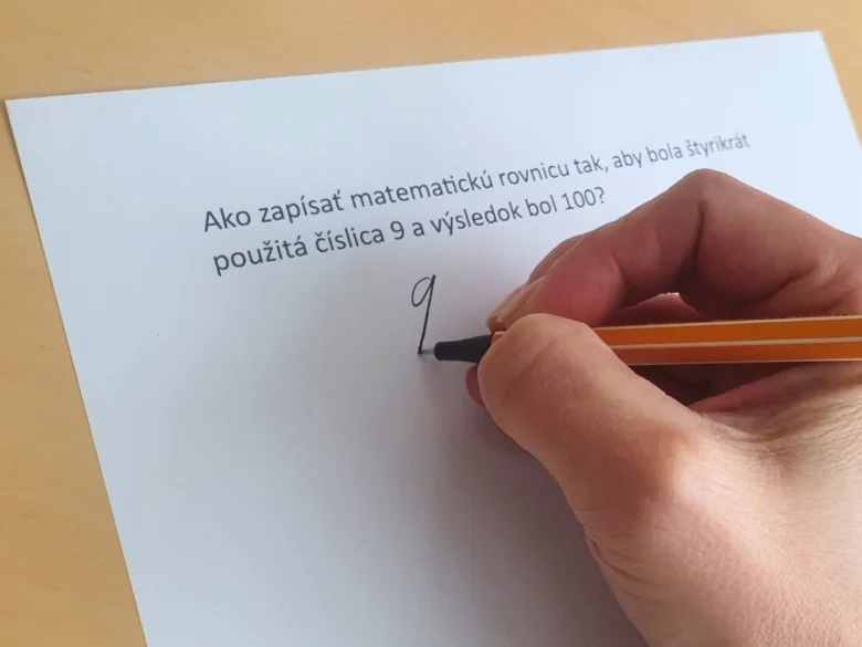 Ruka píše číslu devět při řešení matematické hádanky na papír.