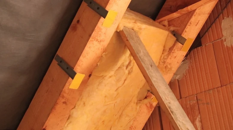 Minerální vata mezi dřevěnými trámy ve stropu nebo zdi.
