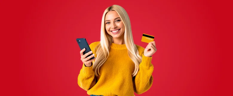 Žena s mobilním telefonem a kreditní kartou na červeném pozadí.