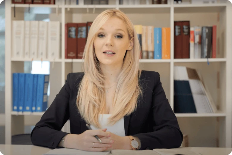 Profesionální žena sedící u stolu v kanceláři s knihovnou.