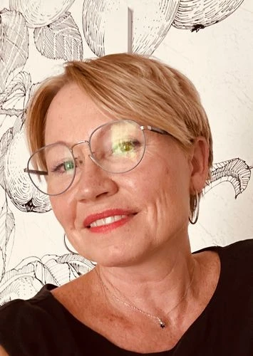 Portrétní fotografie ženy s brýlemi na pozadí botanické ilustrace.