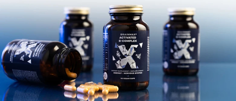 Fľaše s vitamínem B komplex a tobolky na modrém pozadí.