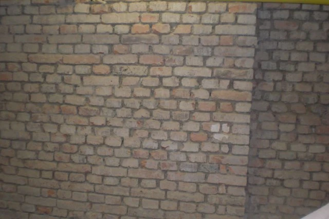 Stará cihlová zeď s viditelnými spármi a texturou.