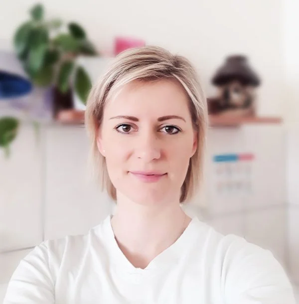Portrét ženy v bílé košili, která se usmívá.