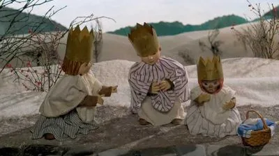 Tři dřevěné figurky Tří králů sedící na sněhu.