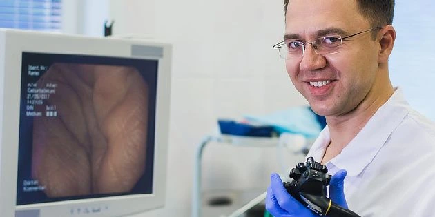 Lékař s endoskopem u monitoru zobrazujícího tlustý střevo.