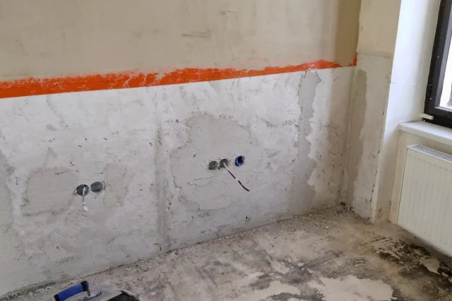 Nerovná stěna v rekonstrukci s viditelnými otvory pro zásuvky