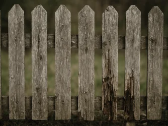 Starý dřevěný plot s vertikálními prkny na pozadí zelené trávy.