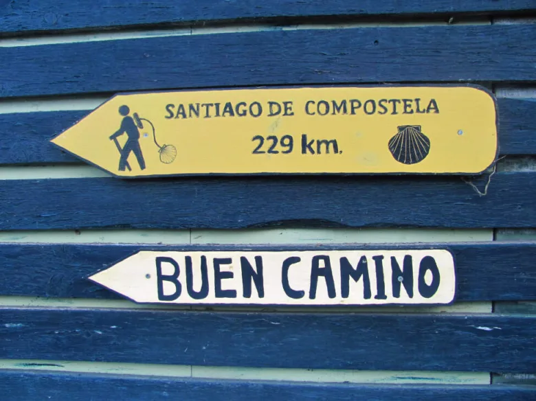 Žlutá tabule s nápisem Santiago de Compostela na modrém dřevě.
