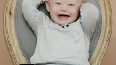 Usměvavé dítě s downovým syndromem sedí na židli.