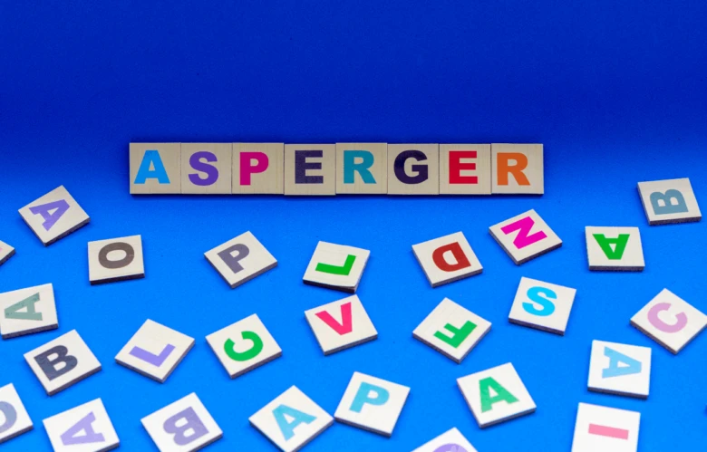 Slovo Asperger napsané barevnými písmenky na modrém pozadí.