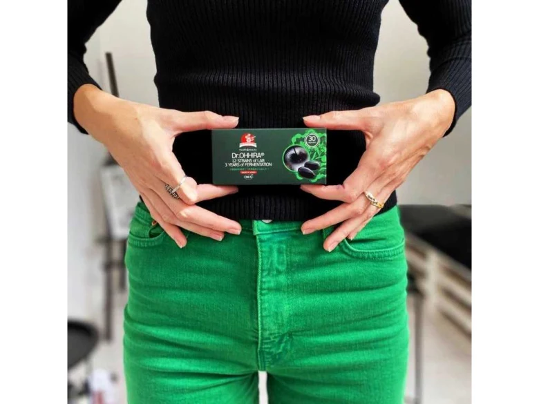 Žena drží krabičku s probiotiky před pasem.