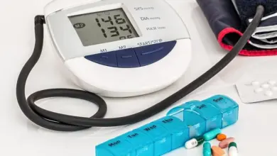 Digitální měřič krevního tlaku s tabletami na bílém pozadí.
