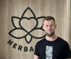Muž stojí před dřevěnou stěnou s logem Herbalife.