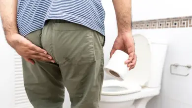 Muž drží toaletní papír u záchodu při průjmu.