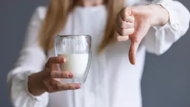 Žena odmítá mléko gestem palce dolů kvůli intoleranci na laktózu.