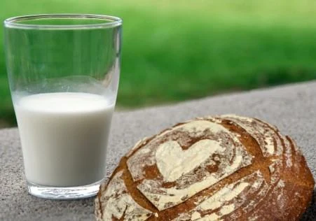 Sklenice mléka s chlebem na kamenném povrchu.