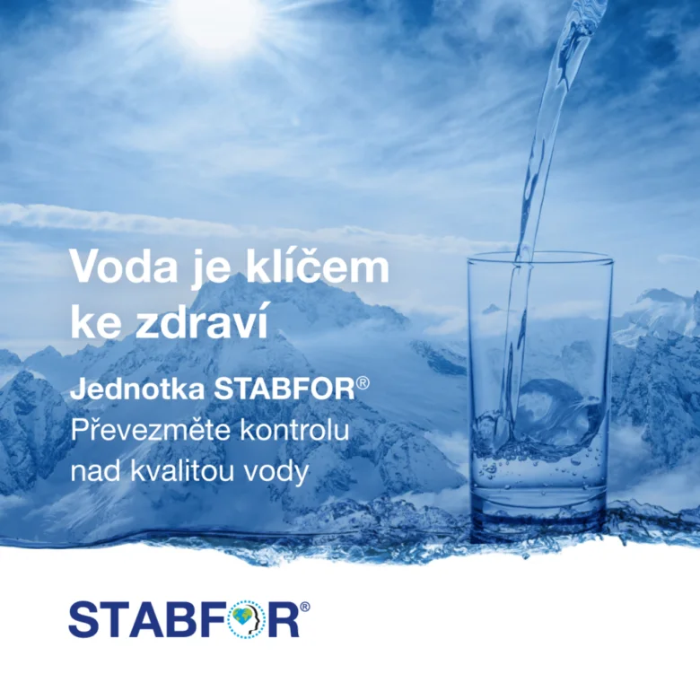 Čistá voda se nalévá do skla s horami na pozadí.