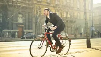 Muž v obleku jezdí na kole po městě.