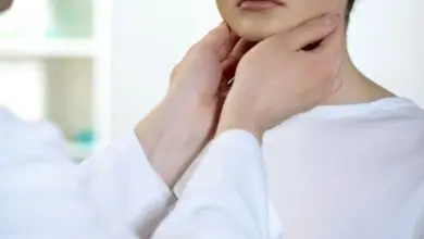 Lékař vyšetřuje hrdlo pacienta rukama.