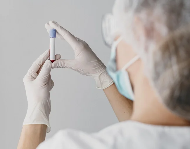 Zdravotnický pracovník drží testovací ampulku pro vyšetření.