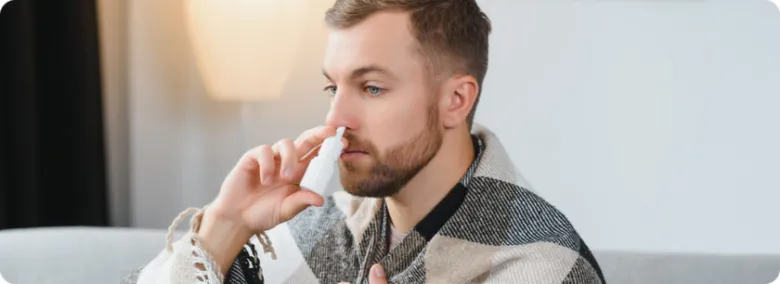 Muž používá nosní sprej pro léčbu zánětu nosohltanu.